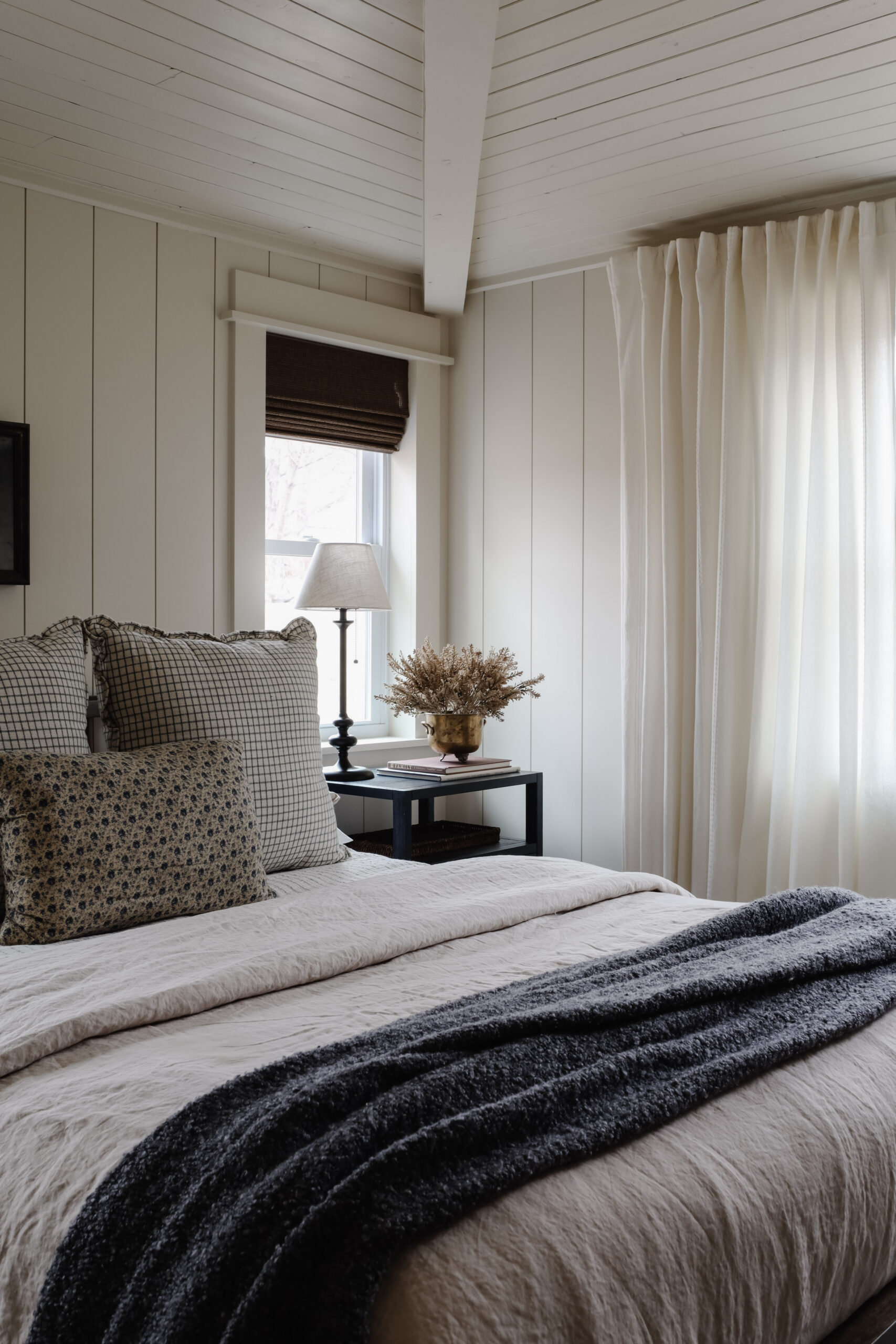 A warm cream bedroom with plank walls and a dark wood nightstand. Bedroom nightstand size guide by Nadine Stay