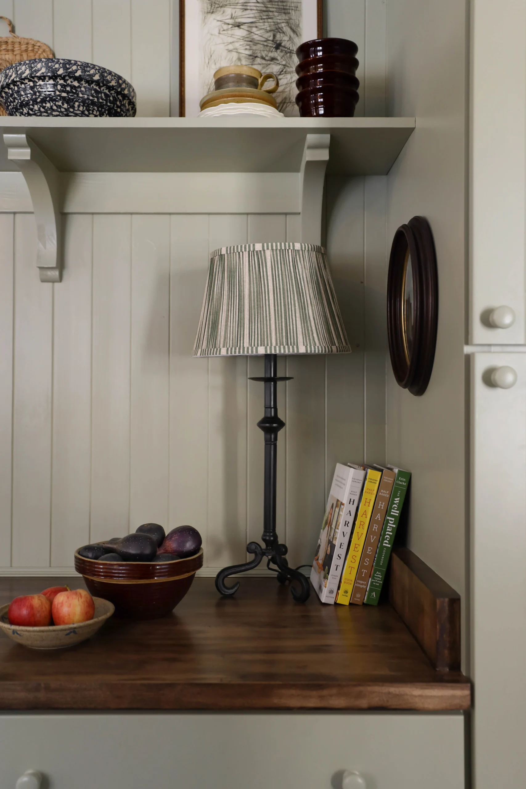 Green striped pleated lamp shade on a candlestick lamp in a kitchen